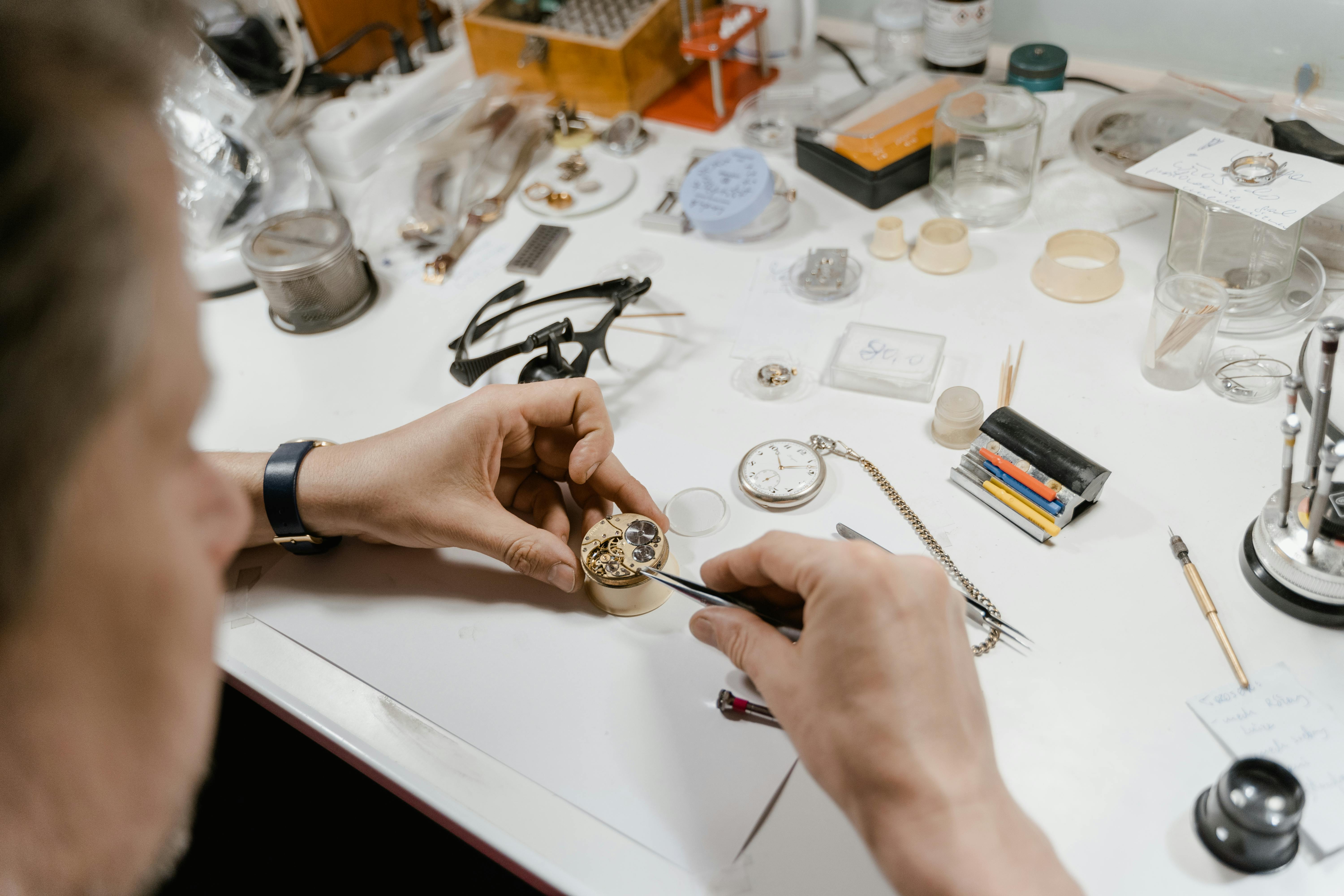 Overhead view of a watchmaker's organized workbench with precision tools spread out